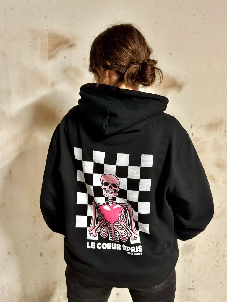 Image actuelle : Gérante de la marque UGLY DUCKY de dos portant un sweat graphique streetwear "Coeur Épris"